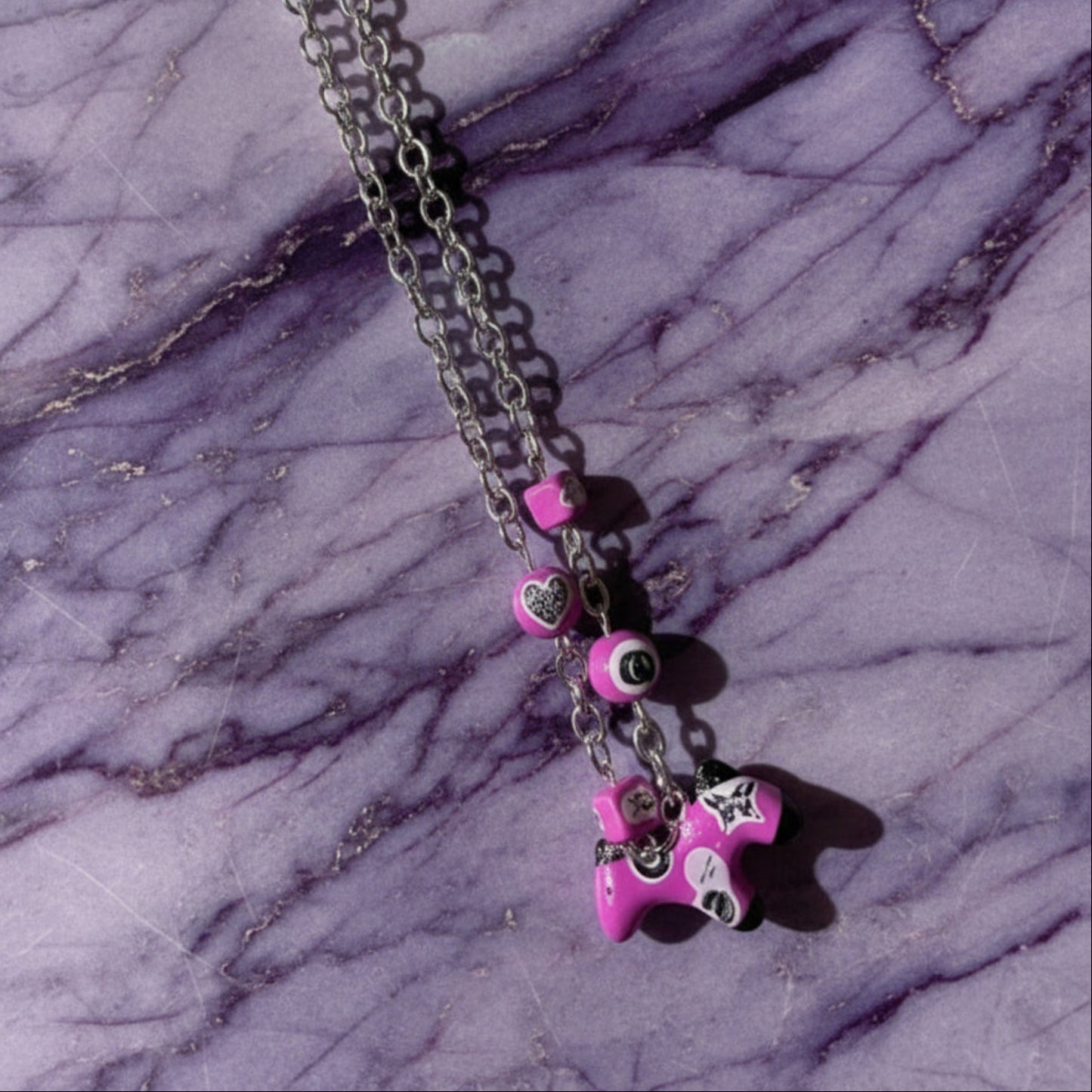 Necklace with pink star-shaped pendant on a purple marble surface