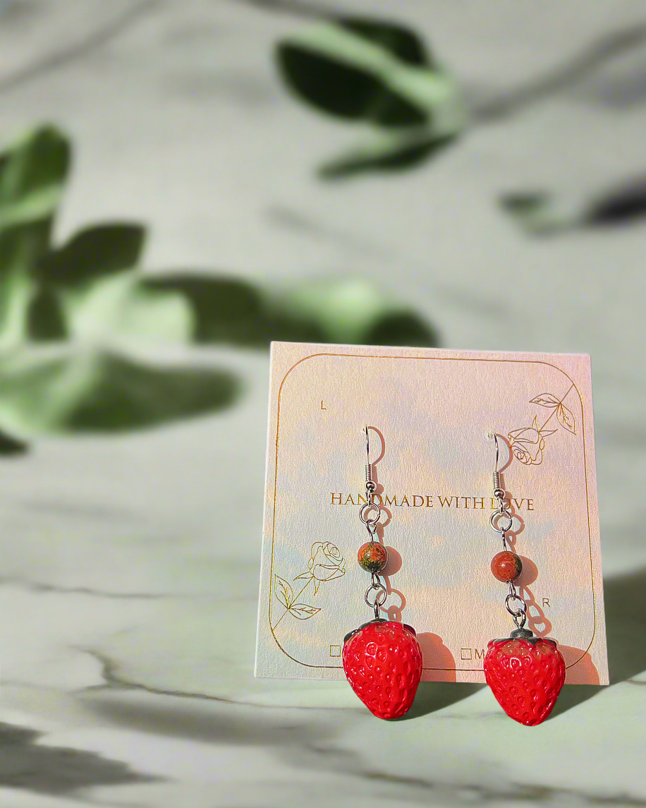 Fairy earrings with strawberry and unakite design on a card, surrounded by fairy illustrations and strawberries.
