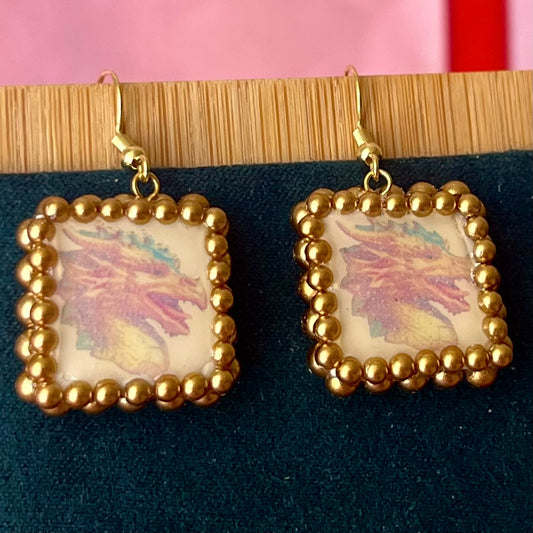 Handmade medieval gold dragon earrings—polymer‑clay dragon charms painted metallic gold, framed with gold pearls, featuring 18k gold‑plated findings and hypoallergenic hooks, perfect fantasy/medievalcore statement jewelry.