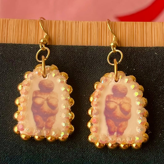 Handmade golden Venus of Willendorf portrait earrings featuring polymer‑clay image‑transfer arch charm (≈1 in), framed with metallic golden pearls and rhinestones, 18k gold‑plated hypoallergenic findings, museumcore/goddesscore art jewelry, gold statement earrings, wearable art, perfect gift for art lovers.