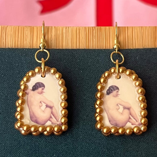 Handmade nude lady earrings featuring bronze polymer‑clay arch charms with an oil‑painting‑style image transfer and a sparkling pearl frame, set on 18k gold‑plated, hypoallergenic findings—perfect museum‑core, renaissance, medieval, coquette, and fairycore jewelry.