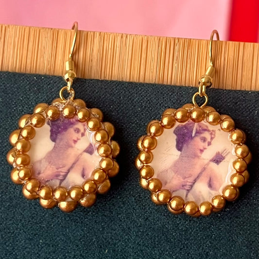 Handmade Artemis earrings featuring bronze polymer‑clay arch charms with an image‑transfer design and a sparkling pearl frame, set on 18k gold‑plated hypoallergenic findings—perfect mythology, Greek‑goddess, renaissance, medieval, museum‑core, coquette, and fairy‑core jewelry.