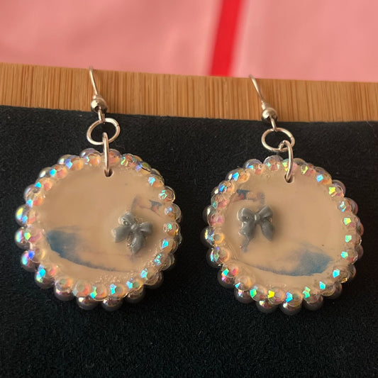 Handcrafted polymer‑clay “kissing swans” earrings with coquette pink bow ties, iridescent pearls, rhinestones, and hypoallergenic 18k gold‑plated findings – a pastel, kawaii, sweet‑lolita, y2k‑style romantic accessory.