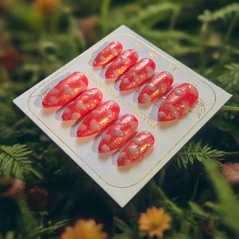 Hot pink nails with a gold shimmer sparkle topped with white fluffy clouds. The pink sky princess nails are on a card which reads "handmade with love"
