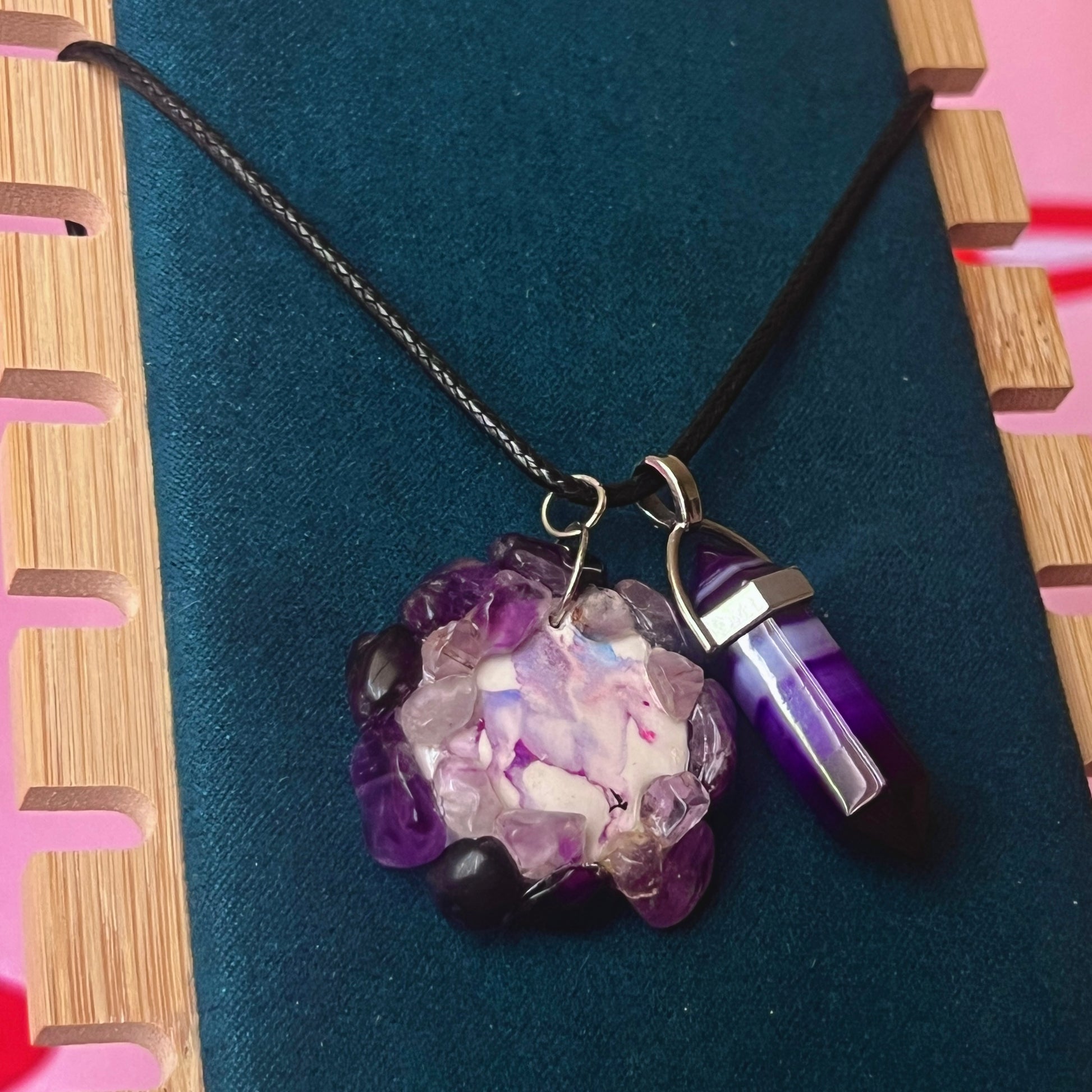 Handmade polymer clay pegasus charm necklace bedazzled with real amethyst crystals, paired with a medium statement amethyst pendant on a 22-inch black vegan leather chain.