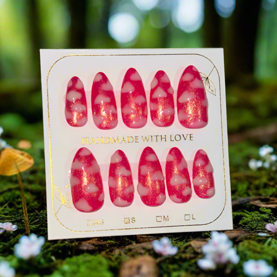 Hot pink nails with a gold shimmer sparkle topped with white fluffy clouds. The pink sky princess nails are on a card which reads "handmade with love"