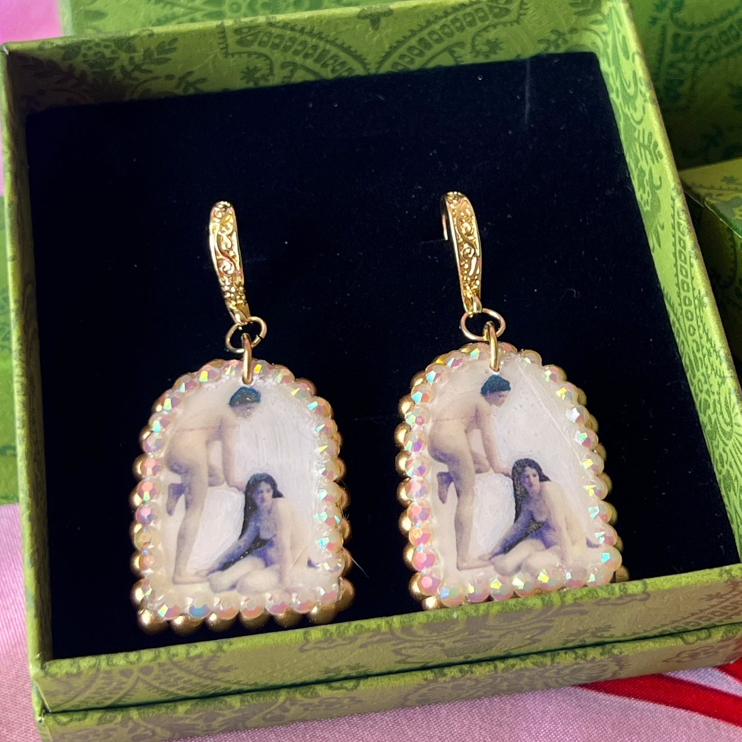 A wearable‑art pair of Bouguereau Bathers earrings — white polymer‑clay arch charms printed with “The Bathers” artwork of two nude women, one standing and one seated on the ground, embellished with gold pearls and clear rhinestones, on 18k gold‑plated hooks; perfect museum‑core, renaissance‑core, coquette statement earrings for art lovers.