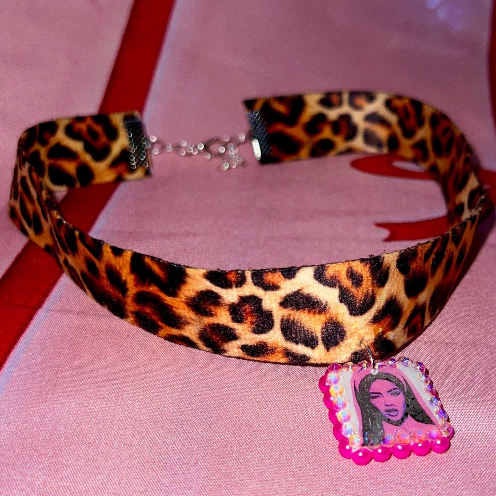 Cheetah print choker necklace — 16" soft fabric cheetah print choker with neon hot pink Y2K nun charm handmade in polymer clay and bedazzled with iridescent beads. Gift-ready green Victorian-patterned box. Whimsigoth grunge indie statement choker; ready to ship in 1–3 business days.