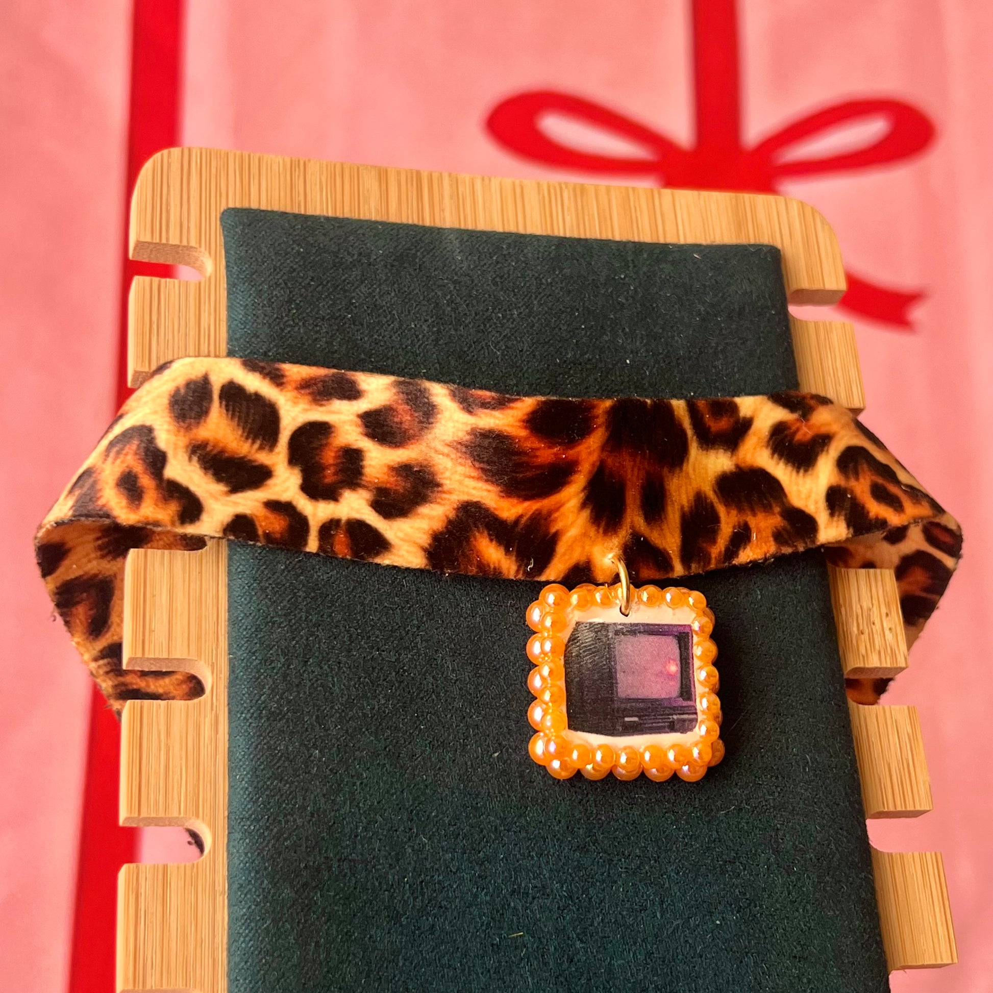 Cheetah print TV charm choker — soft cheetah print choker with handmade polymer clay retro Y2K television charm framed by bright orange pearls. Adjustable fit ~14–16" with extension chain. Gift-ready green Victorian-patterned box + bow. Wearable nostalgia kitsch jewelry; ready to ship in 1–3 days.