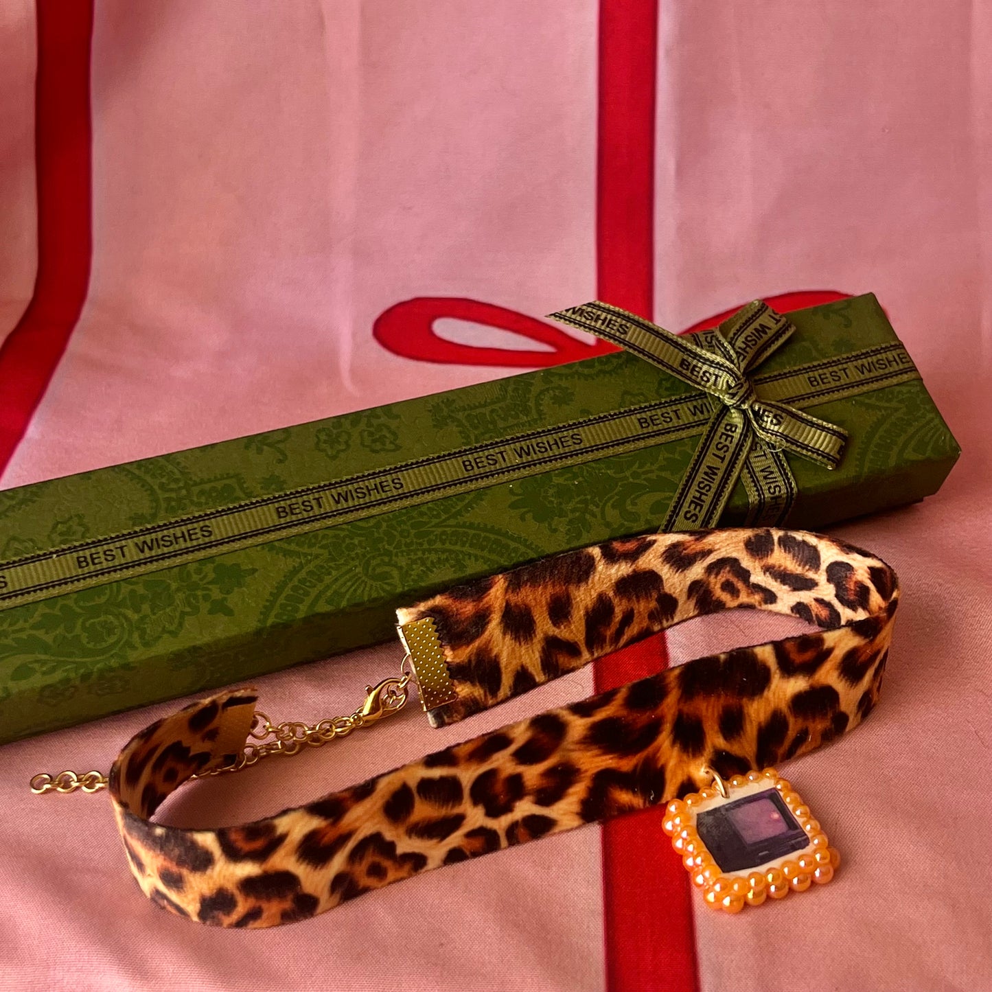 Cheetah print TV charm choker — soft cheetah print choker with handmade polymer clay retro Y2K television charm framed by bright orange pearls. Adjustable fit ~14–16" with extension chain. Gift-ready green Victorian-patterned box + bow. Wearable nostalgia kitsch jewelry; ready to ship in 1–3 days.