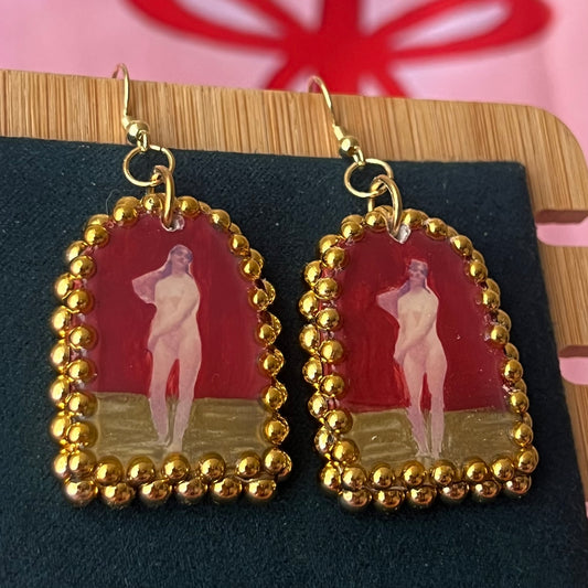 Handmade polymer‑clay arch‑shaped earrings featuring a nude lady art portrait on a deep red background, framed with pearls and finished with 18k gold‑plated hypoallergenic hooks—perfect romantic, coquette, renaissance‑style statement piece.