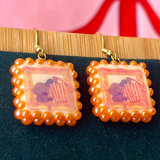 Handmade queer pride earrings featuring polymer clay square charms and iridescent orange pearl drops on 18k gold‑plated hypoallergenic findings, a lightweight geometric dangle that celebrates LGBTQ pride.