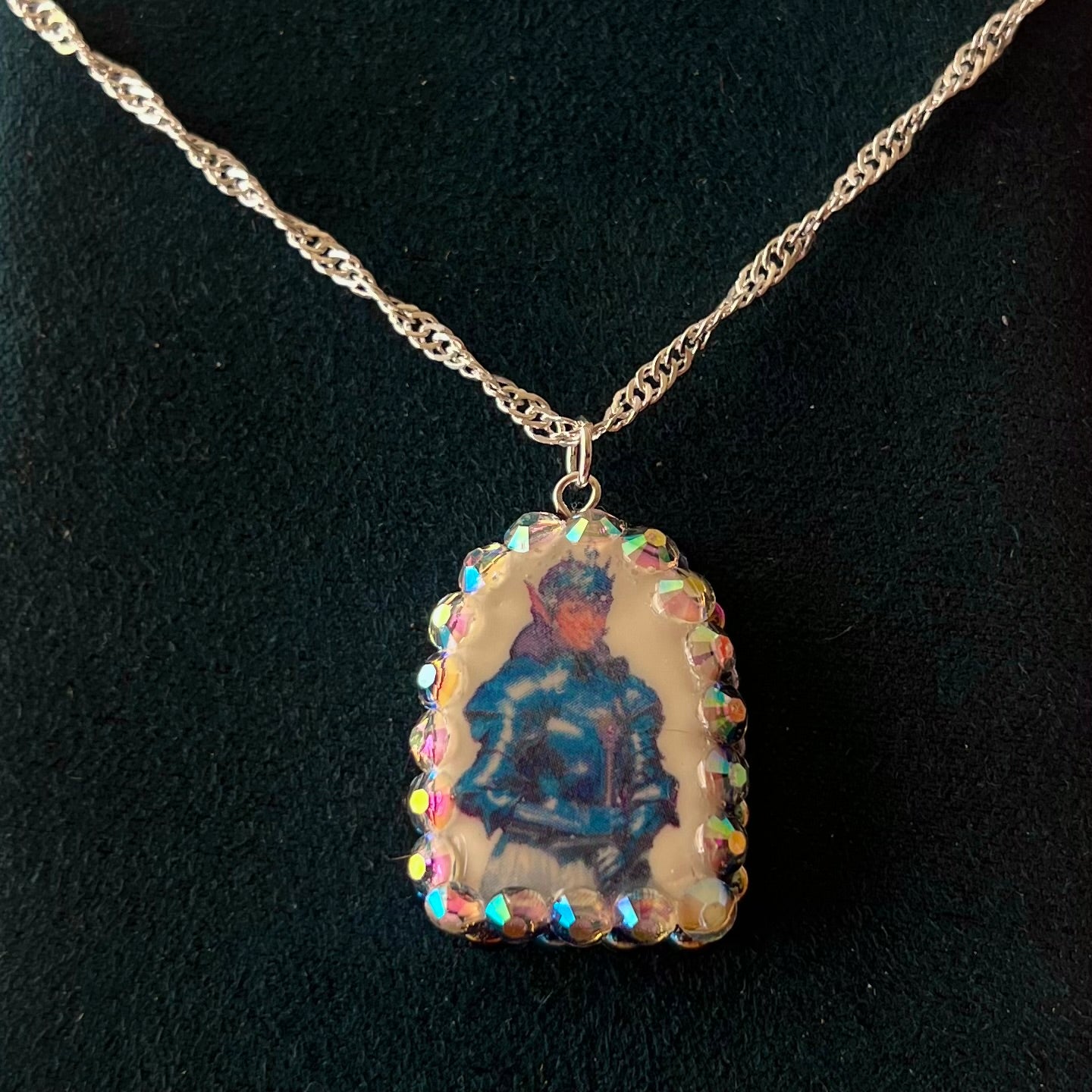 Elf Knight Necklace by Olive Made — a handmade polymer clay fantasy charm necklace featuring a medieval-inspired elf in knight armor, embellished with iridescent pearls and sparkling rhinestones. This whimsical medievalcore / fairycore statement piece comes on a 20” 925 sterling silver chain and arrives gift-ready in a Victorian patterned box with a green bow. Perfect for renaissance fair outfits, elfcore styling, and storybook gifting. Ready to ship in 1–3 business days.