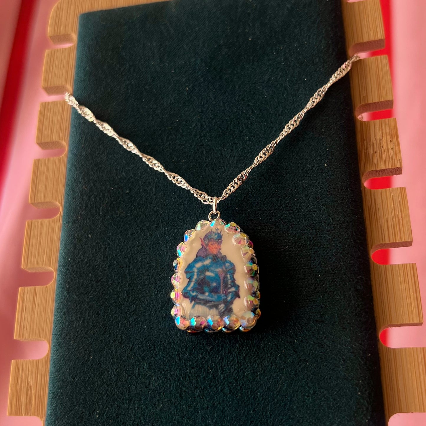 Elf Knight Necklace by Olive Made — a handmade polymer clay fantasy charm necklace featuring a medieval-inspired elf in knight armor, embellished with iridescent pearls and sparkling rhinestones. This whimsical medievalcore / fairycore statement piece comes on a 20” 925 sterling silver chain and arrives gift-ready in a Victorian patterned box with a green bow. Perfect for renaissance fair outfits, elfcore styling, and storybook gifting. Ready to ship in 1–3 business days.