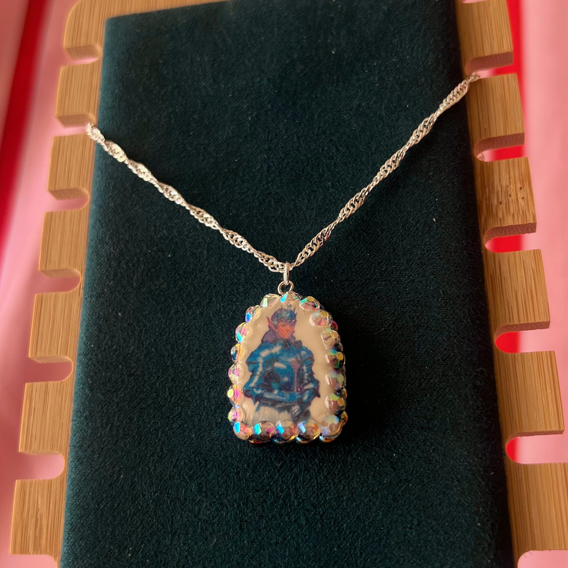 Elf Knight Necklace by Olive Made — a handmade polymer clay fantasy charm necklace featuring a medieval-inspired elf in knight armor, embellished with iridescent pearls and sparkling rhinestones. This whimsical medievalcore / fairycore statement piece comes on a 20” 925 sterling silver chain and arrives gift-ready in a Victorian patterned box with a green bow. Perfect for renaissance fair outfits, elfcore styling, and storybook gifting. Ready to ship in 1–3 business days.