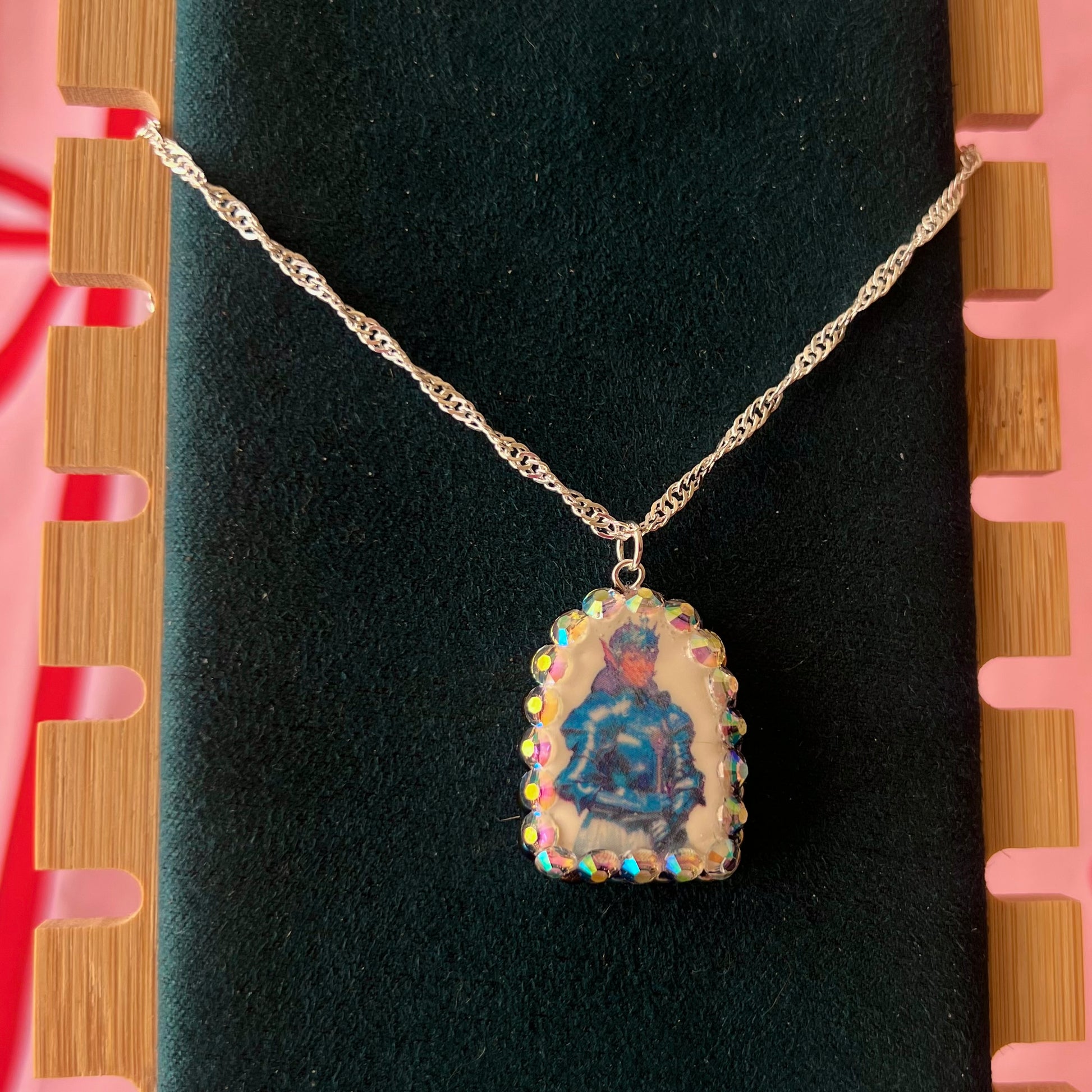 Elf Knight Necklace by Olive Made — a handmade polymer clay fantasy charm necklace featuring a medieval-inspired elf in knight armor, embellished with iridescent pearls and sparkling rhinestones. This whimsical medievalcore / fairycore statement piece comes on a 20” 925 sterling silver chain and arrives gift-ready in a Victorian patterned box with a green bow. Perfect for renaissance fair outfits, elfcore styling, and storybook gifting. Ready to ship in 1–3 business days.