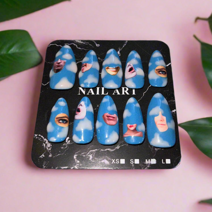 Set of blue nail art designs on a black marble-style tray with a pink background and green leaves.