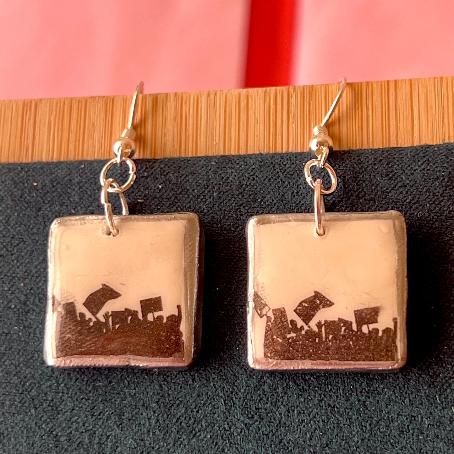 Alt text: Activist “for the people” protest earrings featuring handmade polymer clay silhouette charms with a silver‑black metallic finish, silver‑plated hypoallergenic hooks, and bold protest jewelry style.