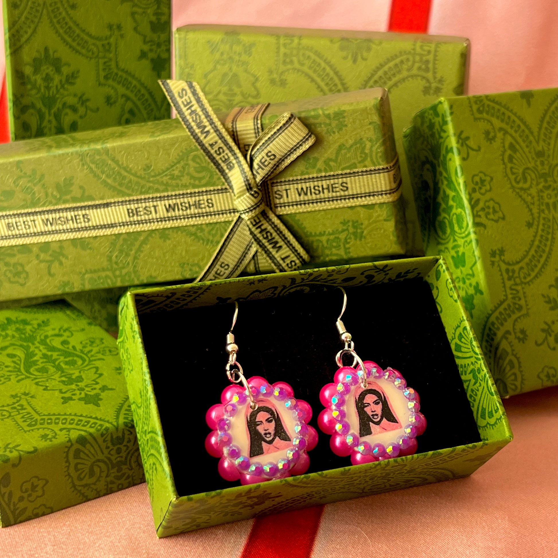 Alt text: Hot pink Y2K nun earrings featuring handmade polymer clay charms bedazzled with iridescent beads, silver plated hypoallergenic hooks, and whimsical gothic, grunge, punk, pink, Y2K style—perfect gift‑ready earrings in a cute green Victorian‑patterned box.