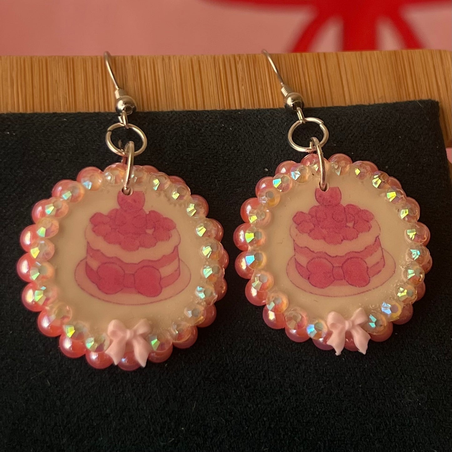 Alt text: Handcrafted polymer‑clay jelly cake earrings with pink coquette bows, iridescent pearls and rhinestones – a sweet, pastel kawaii accessory perfect for a cute dangle look.