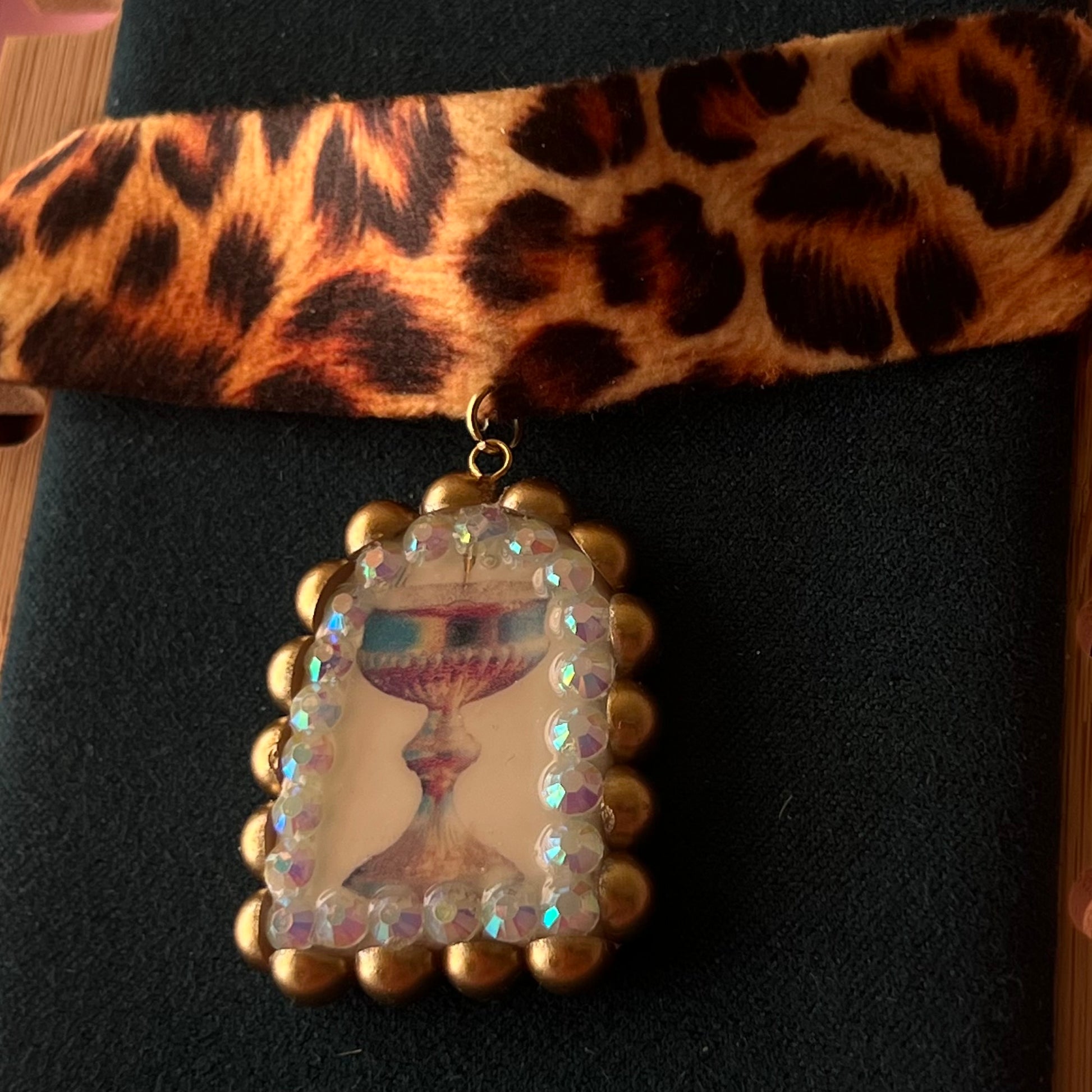 Jungle Elixir choker — soft cheetah print choker with handmade polymer clay fantasy chalice charm framed with bronze pearls and iridescent rhinestones. Adjustable fit ~14–16" with extension chain. Gift-ready green Victorian-patterned box + bow. Ready to ship in 1–3 days.
