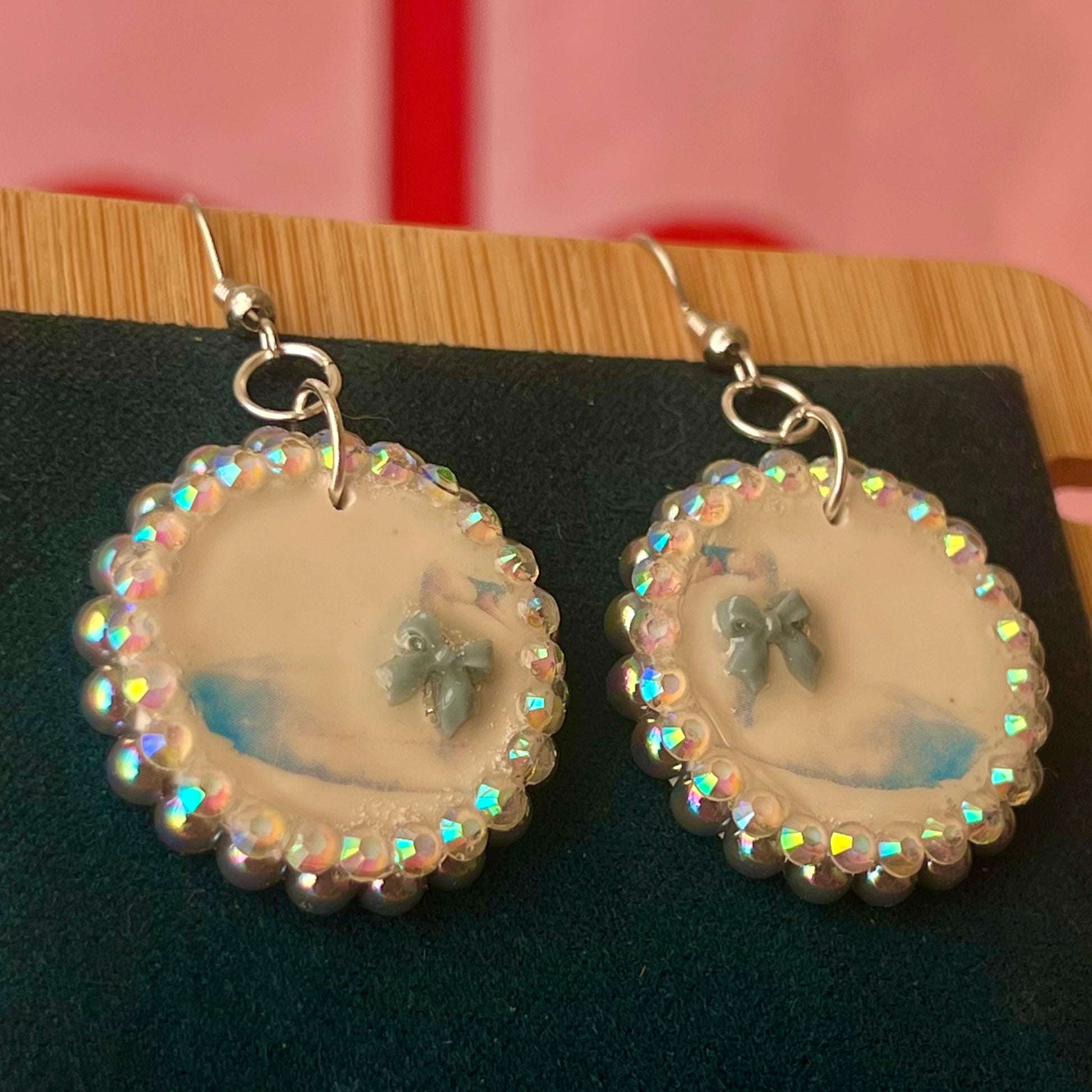 Handcrafted polymer‑clay “kissing swans” earrings with coquette pink bow ties, iridescent pearls, rhinestones, and hypoallergenic 18k gold‑plated findings – a pastel, kawaii, sweet‑lolita, y2k‑style romantic accessory.