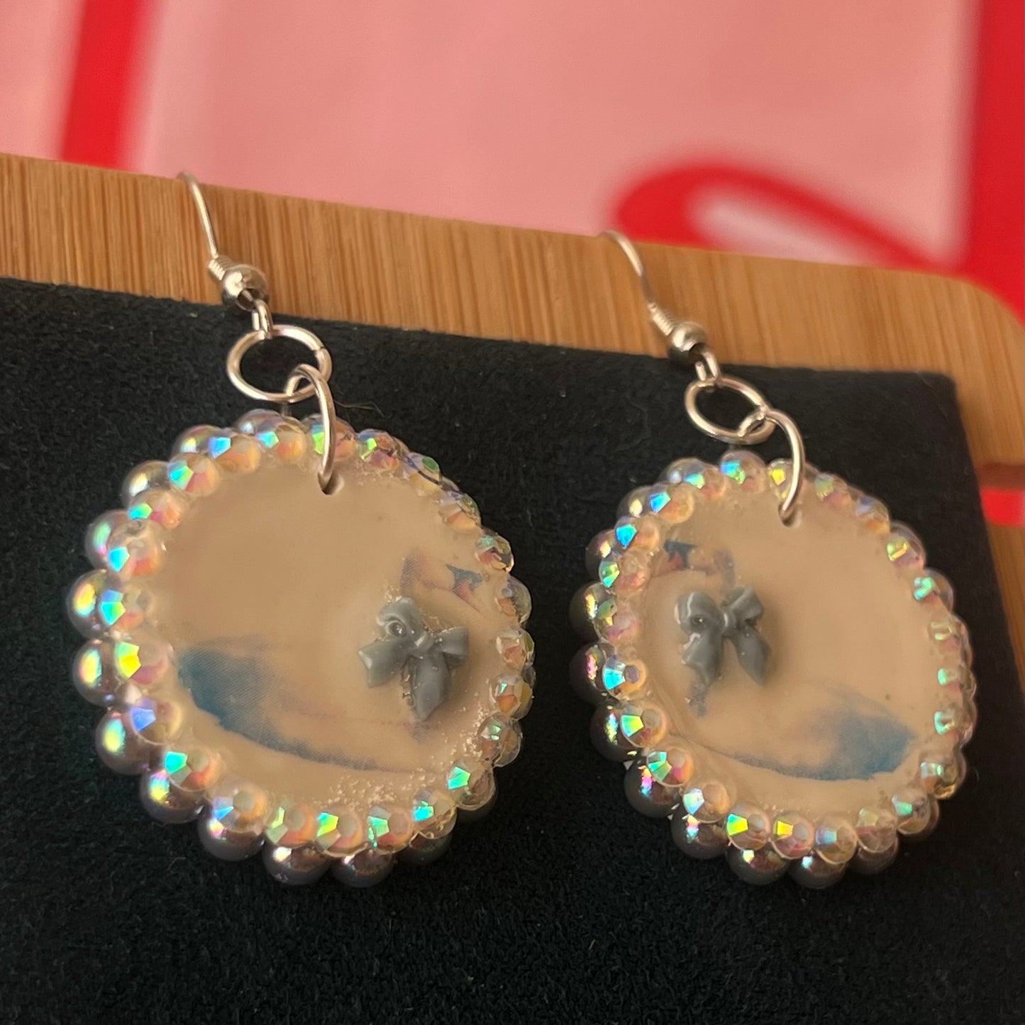 Handcrafted polymer‑clay “kissing swans” earrings with coquette pink bow ties, iridescent pearls, rhinestones, and hypoallergenic 18k gold‑plated findings – a pastel, kawaii, sweet‑lolita, y2k‑style romantic accessory.
