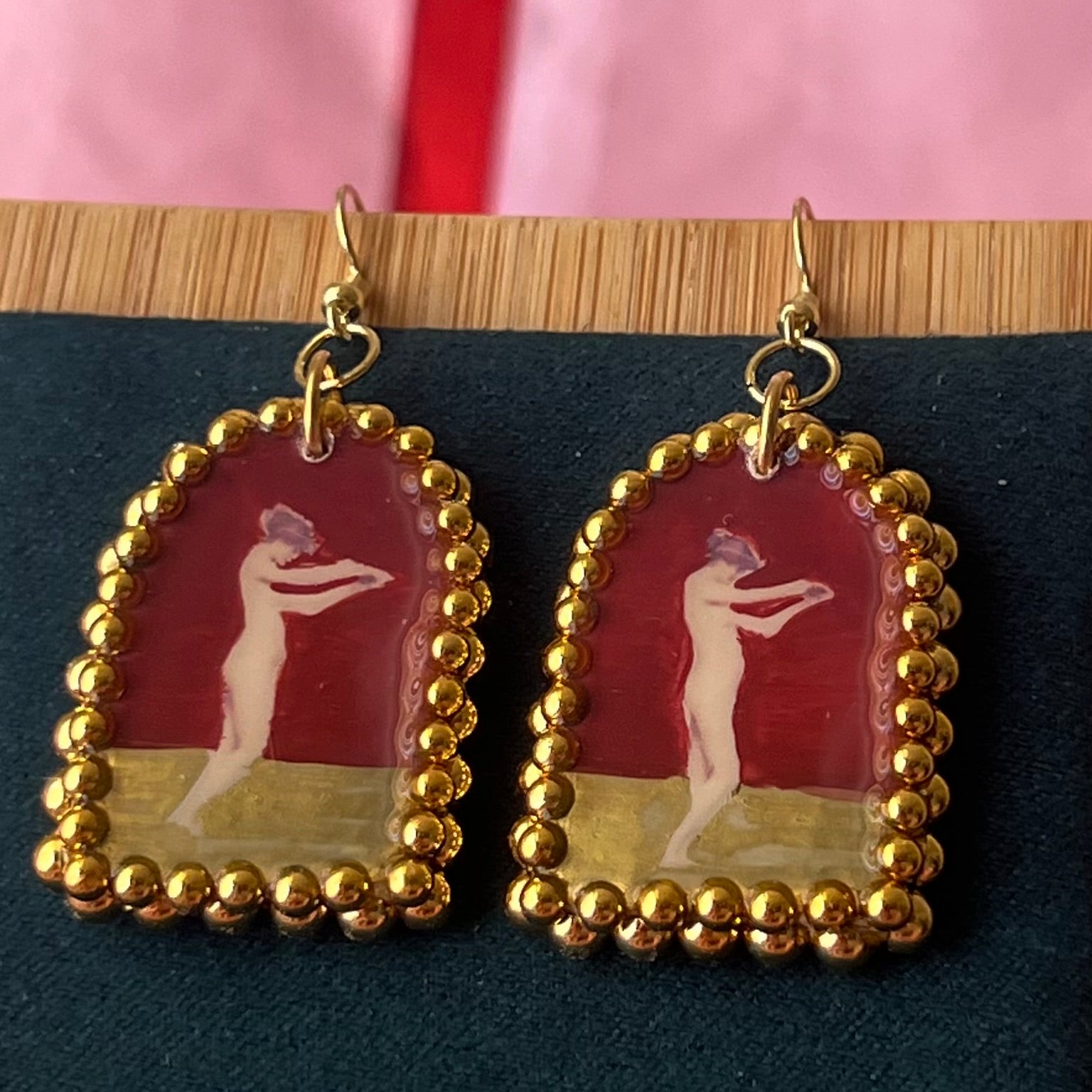 Handmade polymer‑clay arch‑shaped earrings featuring a nude lady art portrait on a deep red background, framed with pearls and finished with 18k gold‑plated hypoallergenic hooks—perfect romantic, coquette, renaissance‑style statement piece.