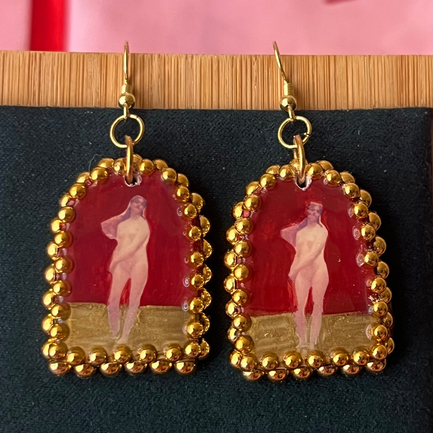 Handmade polymer‑clay arch‑shaped earrings featuring a nude lady art portrait on a deep red background, framed with pearls and finished with 18k gold‑plated hypoallergenic hooks—perfect romantic, coquette, renaissance‑style statement piece.