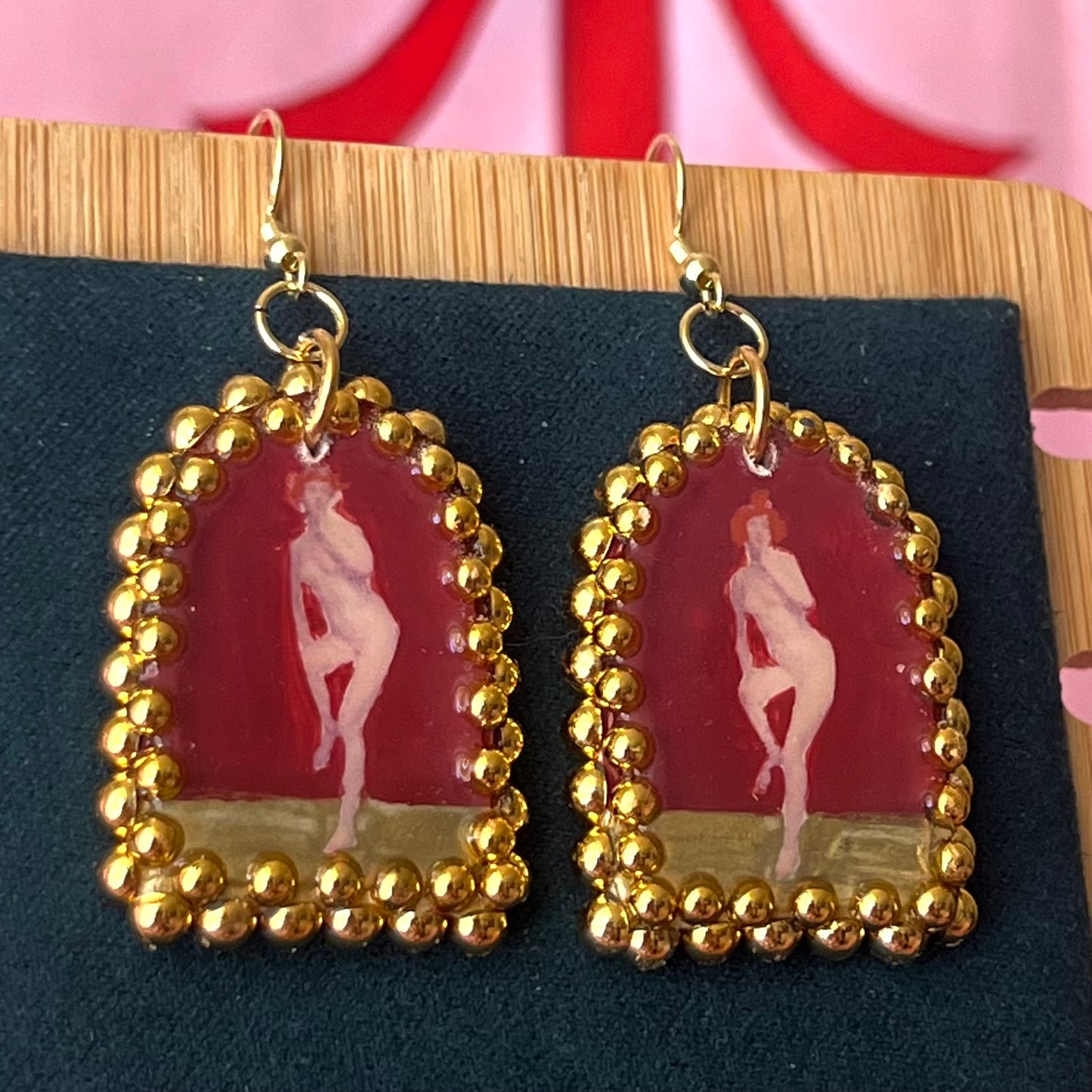 Handmade polymer‑clay arch‑shaped earrings featuring a nude lady art portrait on a deep red background, framed with pearls and finished with 18k gold‑plated hypoallergenic hooks—perfect romantic, coquette, renaissance‑style statement piece.