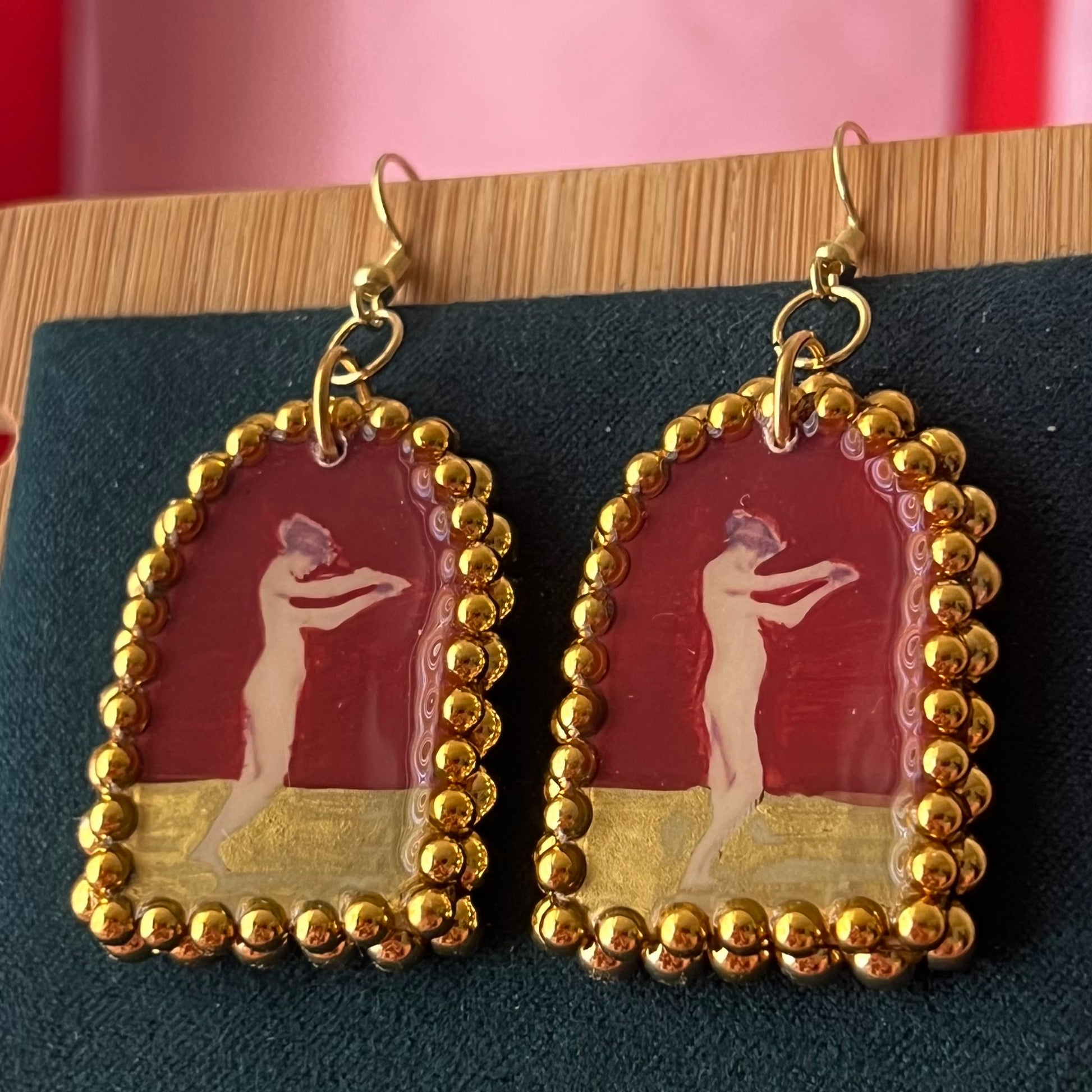 Handmade polymer‑clay arch‑shaped earrings featuring a nude lady art portrait on a deep red background, framed with pearls and finished with 18k gold‑plated hypoallergenic hooks—perfect romantic, coquette, renaissance‑style statement piece.