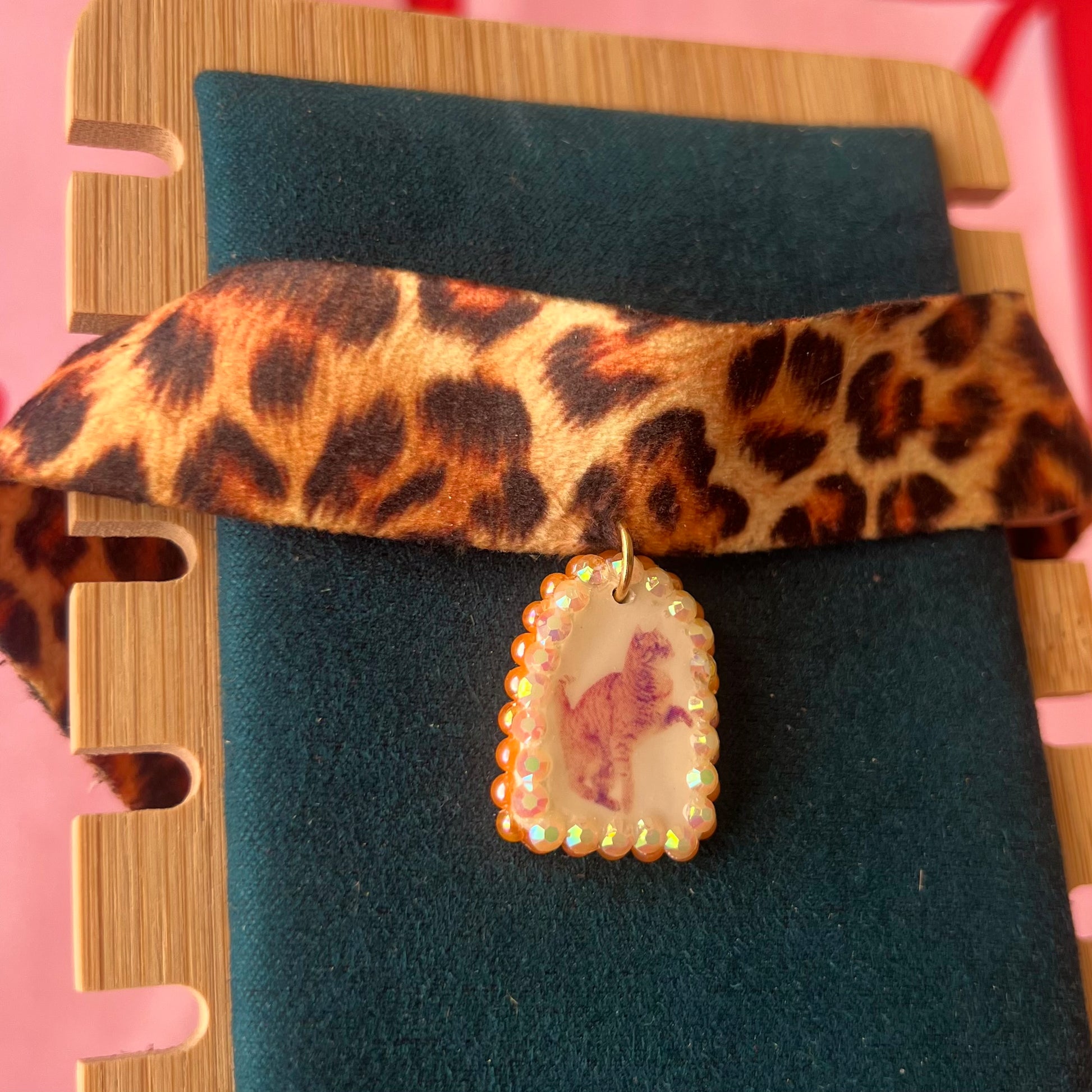 Orange cat charm choker — soft cheetah print choker with handmade polymer clay orange cat charm framed by bright orange pearls. Adjustable fit ~14–16" with extension chain. Gift-ready green Victorian-patterned box + bow. Y2K kitsch cat jewelry; ready to ship in 1–3 days.