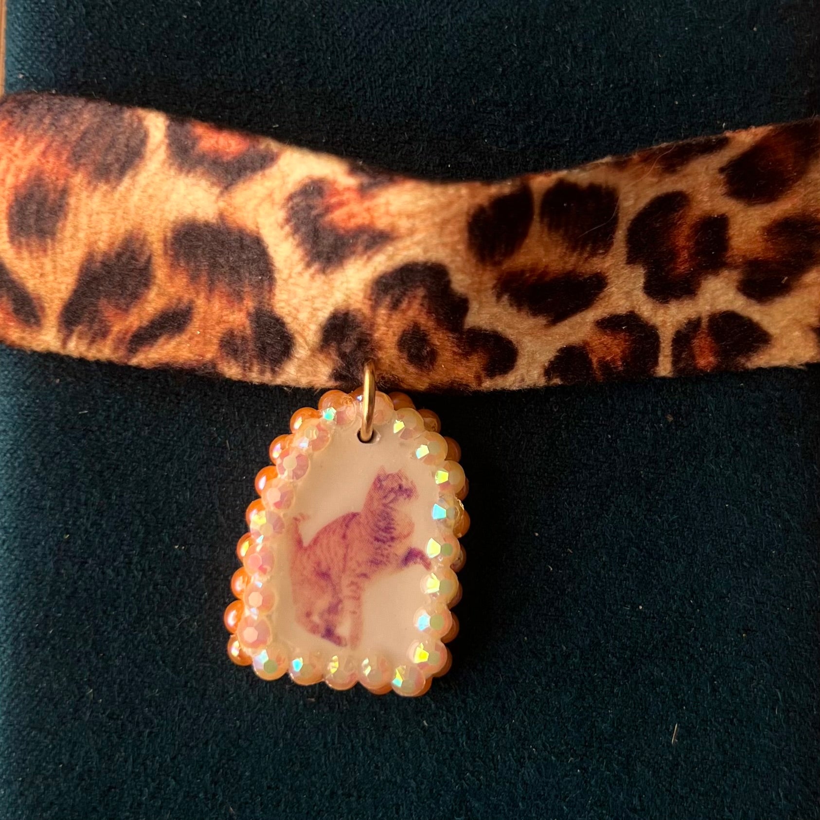 Orange cat charm choker — soft cheetah print choker with handmade polymer clay orange cat charm framed by bright orange pearls. Adjustable fit ~14–16" with extension chain. Gift-ready green Victorian-patterned box + bow. Y2K kitsch cat jewelry; ready to ship in 1–3 days.