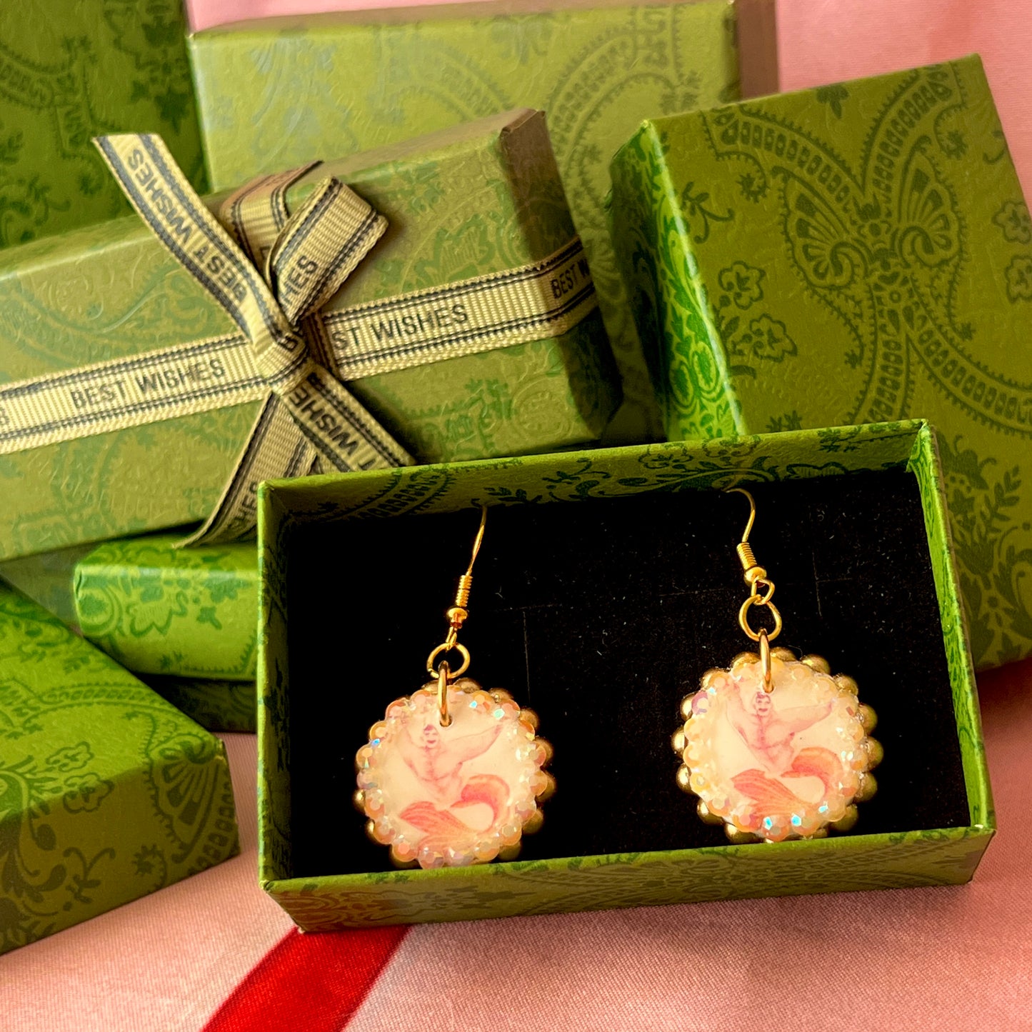 Handmade mermaid‑core earrings featuring a polymer‑clay merman portrait, 3D bow, orange pearls, rhinestones, and 18k gold‑plated hypoallergenic findings—whimsical, nostalgic, wearable art perfect for a statement look.