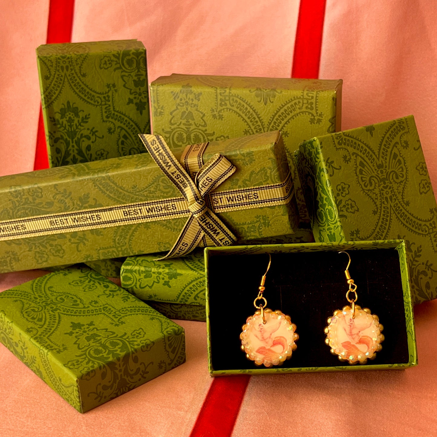 Handmade mermaid‑core earrings featuring a polymer‑clay merman portrait, 3D bow, orange pearls, rhinestones, and 18k gold‑plated hypoallergenic findings—whimsical, nostalgic, wearable art perfect for a statement look.