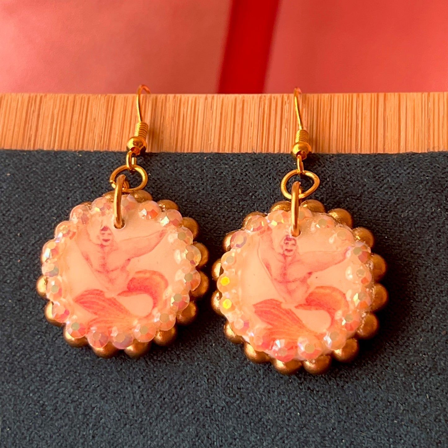 Handmade mermaid‑core earrings featuring a polymer‑clay merman portrait, bronze pearls, rhinestones, and 18k gold‑plated hypoallergenic findings—whimsical, nostalgic, wearable art perfect for a statement look.