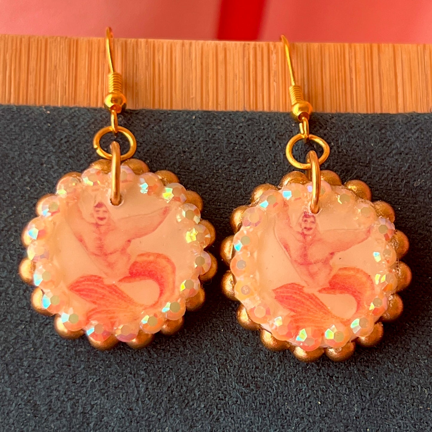 Handmade mermaid‑core earrings featuring a polymer‑clay merman portrait, bronze pearls, rhinestones, and 18k gold‑plated hypoallergenic findings—whimsical, nostalgic, wearable art perfect for a statement look.