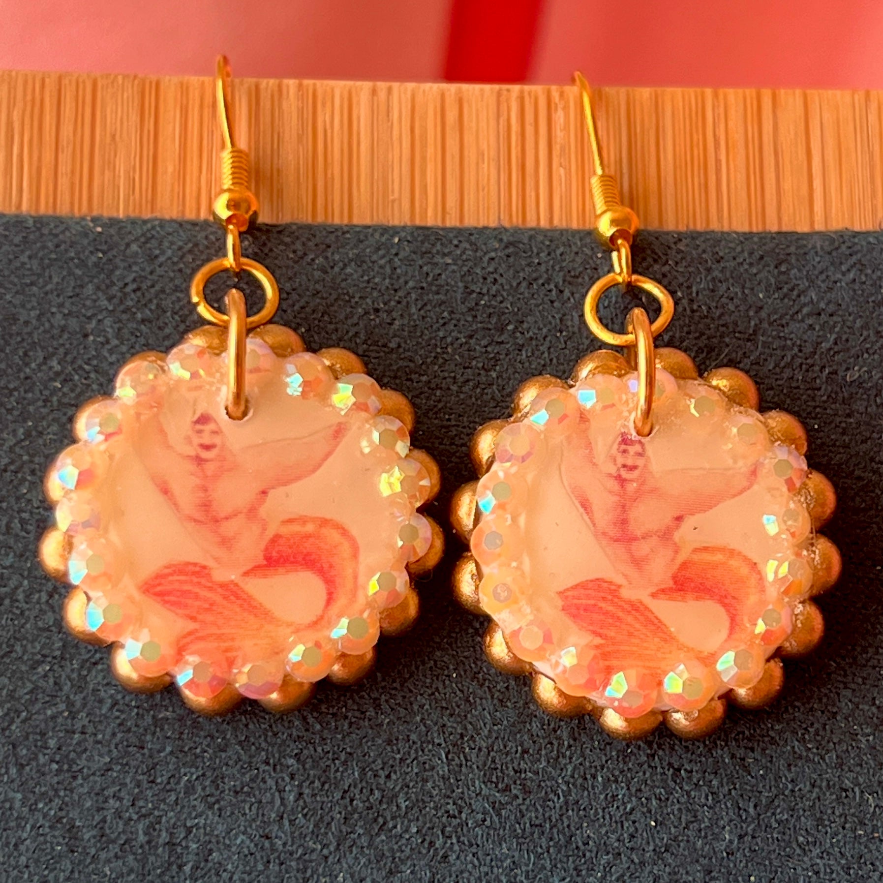 Handmade mermaid‑core earrings featuring a polymer‑clay merman portrait, bronze pearls, rhinestones, and 18k gold‑plated hypoallergenic findings—whimsical, nostalgic, wearable art perfect for a statement look.