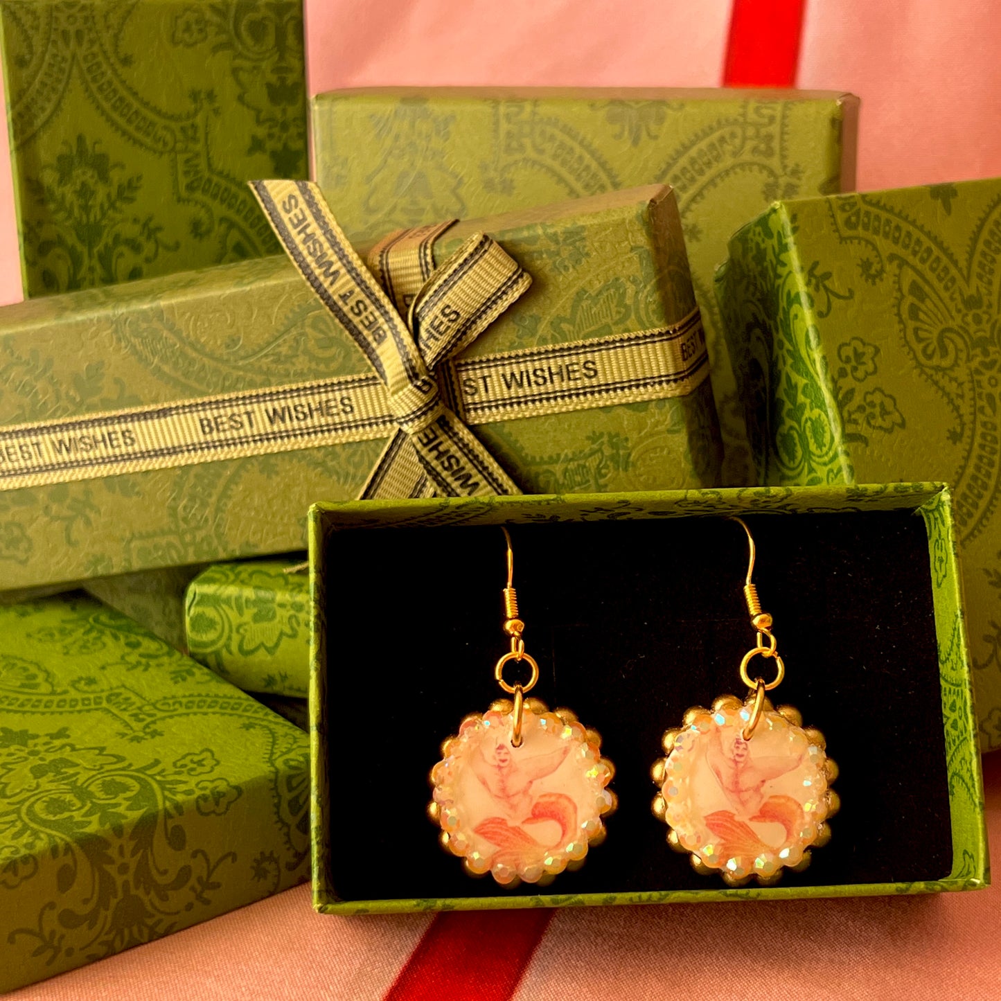 Handmade mermaid‑core earrings featuring a polymer‑clay merman portrait, orange pearls, rhinestones, and 18k gold‑plated hypoallergenic findings—whimsical, nostalgic, wearable art perfect for a statement look.