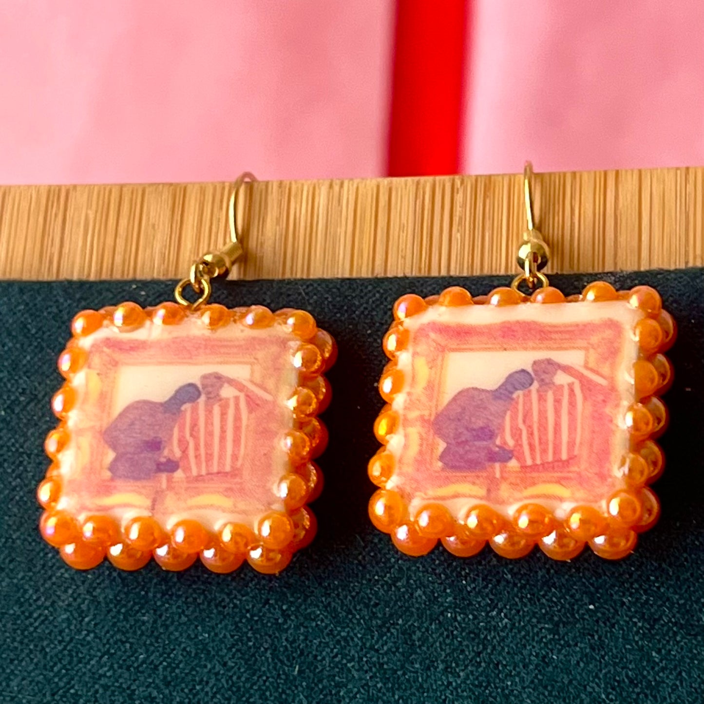 Handmade queer pride earrings featuring polymer clay square charms and iridescent orange pearl drops on 18k gold‑plated hypoallergenic findings, a lightweight geometric dangle that celebrates LGBTQ pride.