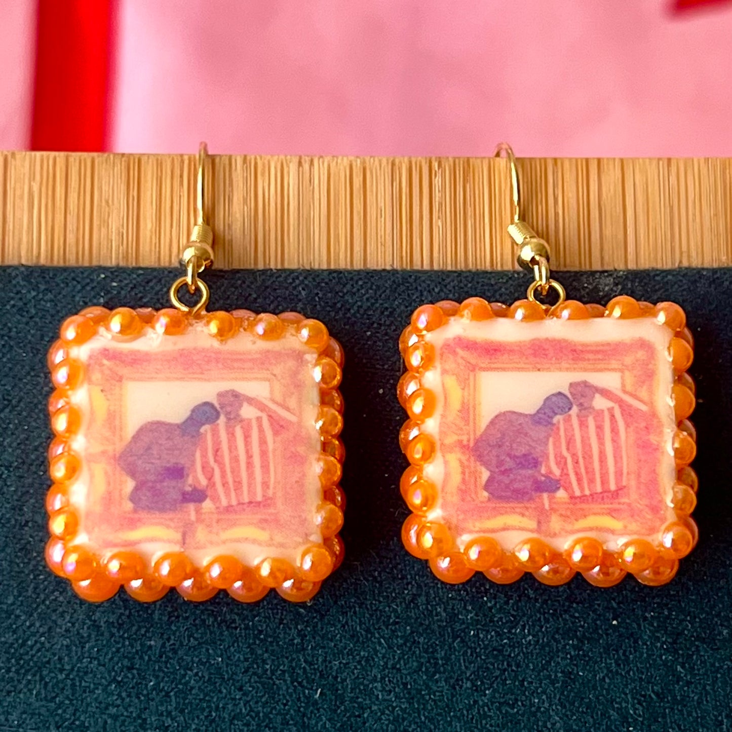Handmade queer pride earrings featuring polymer clay square charms and iridescent orange pearl drops on 18k gold‑plated hypoallergenic findings, a lightweight geometric dangle that celebrates LGBTQ pride.