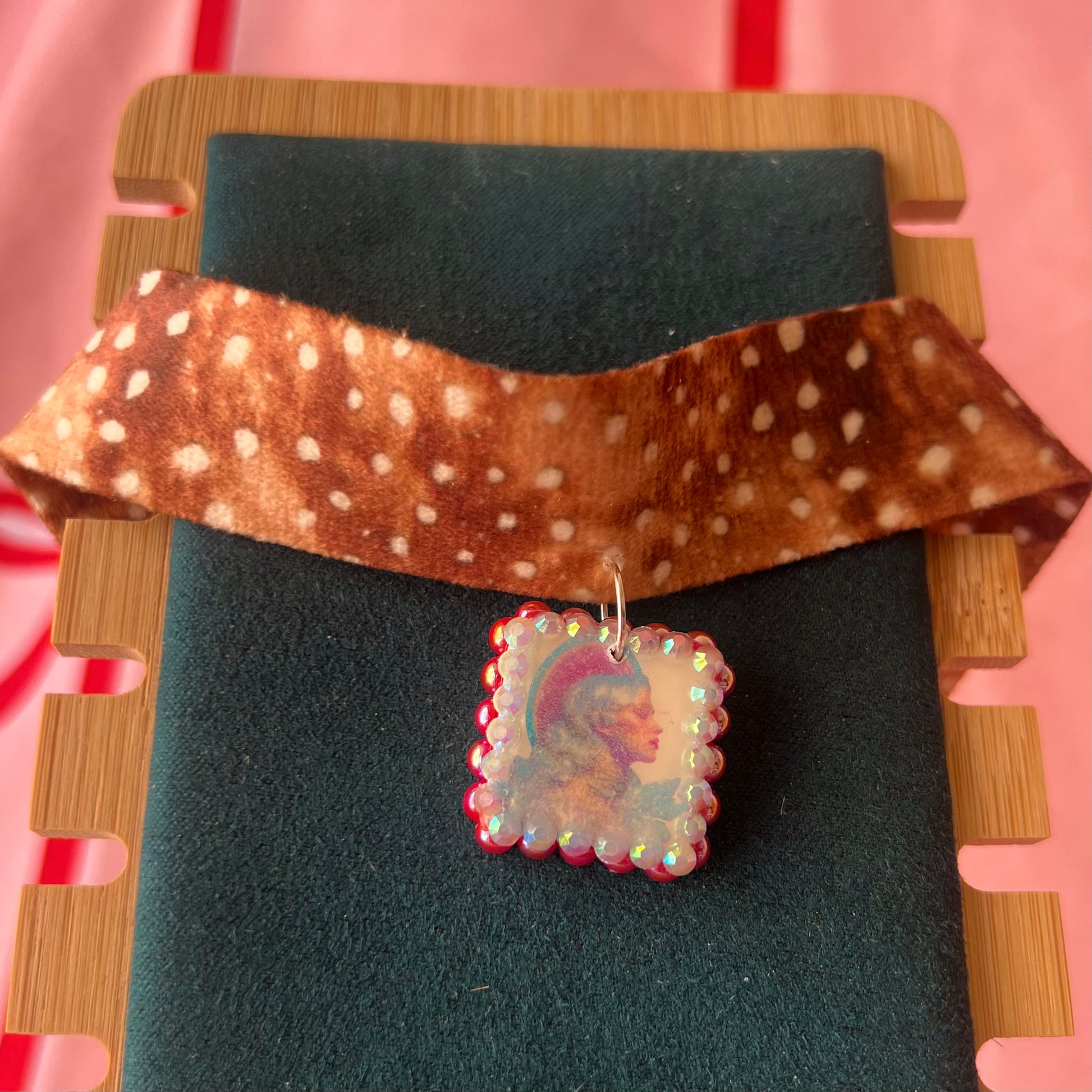 Deer print choker necklace — soft doe/deer print choker (adjustable 13–16") with handmade polymer clay elf portrait charm (approx. 1") bedazzled with iridescent red pearls + rhinestones. Gift-ready Victorian-patterned box with green bow. Fairycore coquette Y2K whimsical jewelry; ready to ship in 1–3 days.