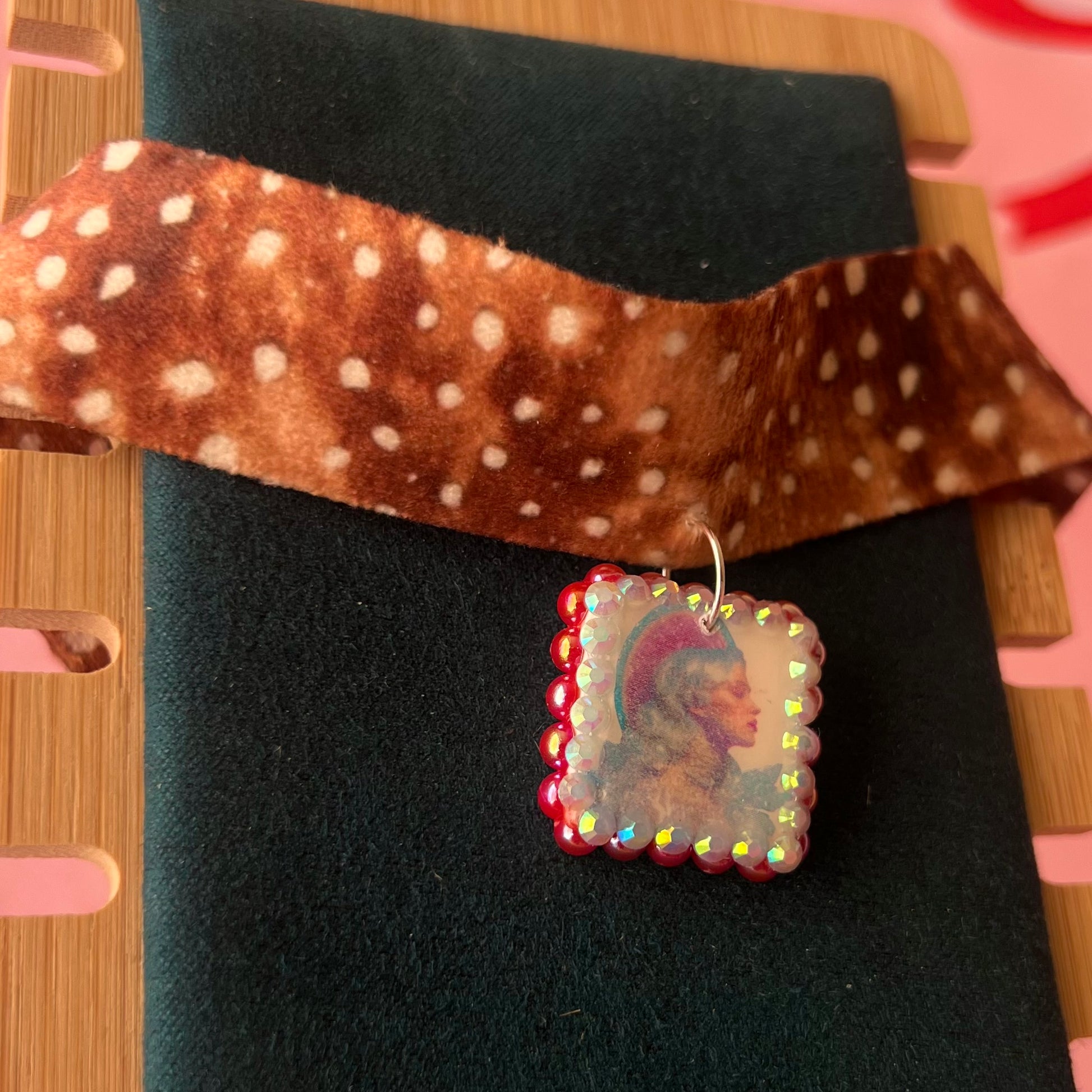 Deer print choker necklace — soft doe/deer print choker (adjustable 13–16") with handmade polymer clay elf portrait charm (approx. 1") bedazzled with iridescent red pearls + rhinestones. Gift-ready Victorian-patterned box with green bow. Fairycore coquette Y2K whimsical jewelry; ready to ship in 1–3 days.