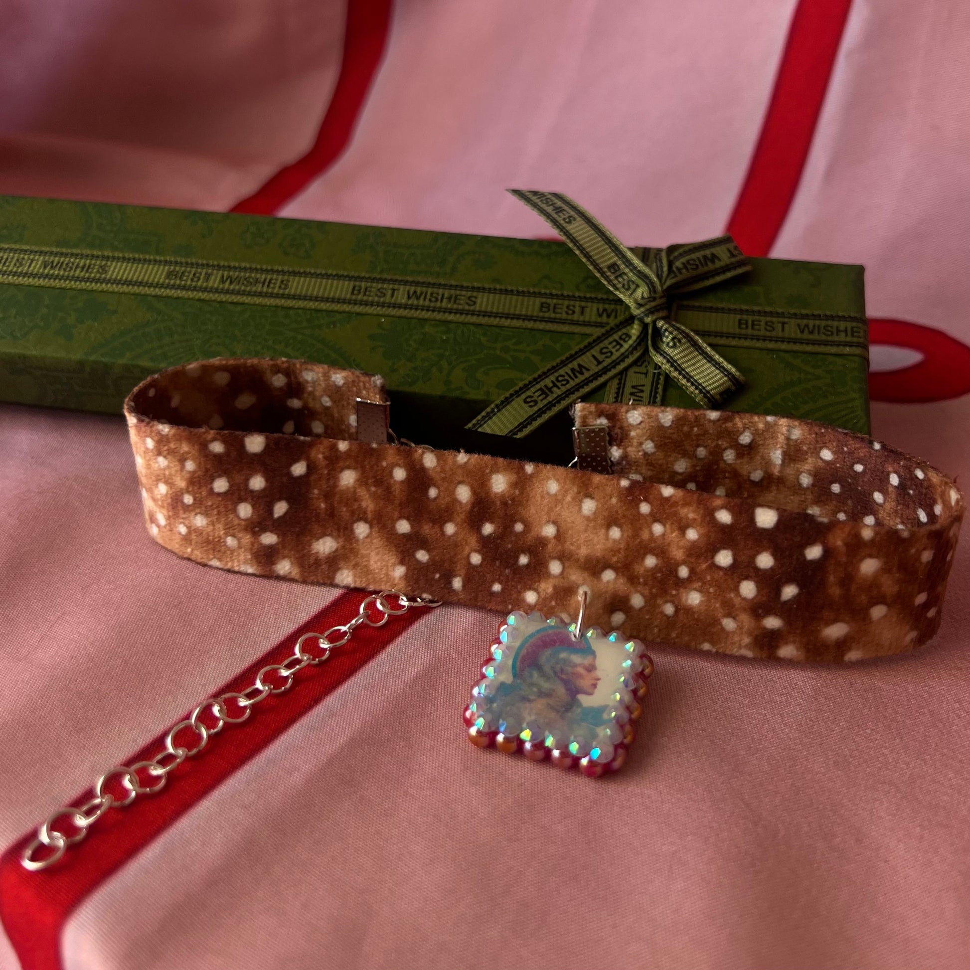 Deer print choker necklace — soft doe/deer print choker (adjustable 13–16") with handmade polymer clay elf portrait charm (approx. 1") bedazzled with iridescent red pearls + rhinestones. Gift-ready Victorian-patterned box with green bow. Fairycore coquette Y2K whimsical jewelry; ready to ship in 1–3 days.