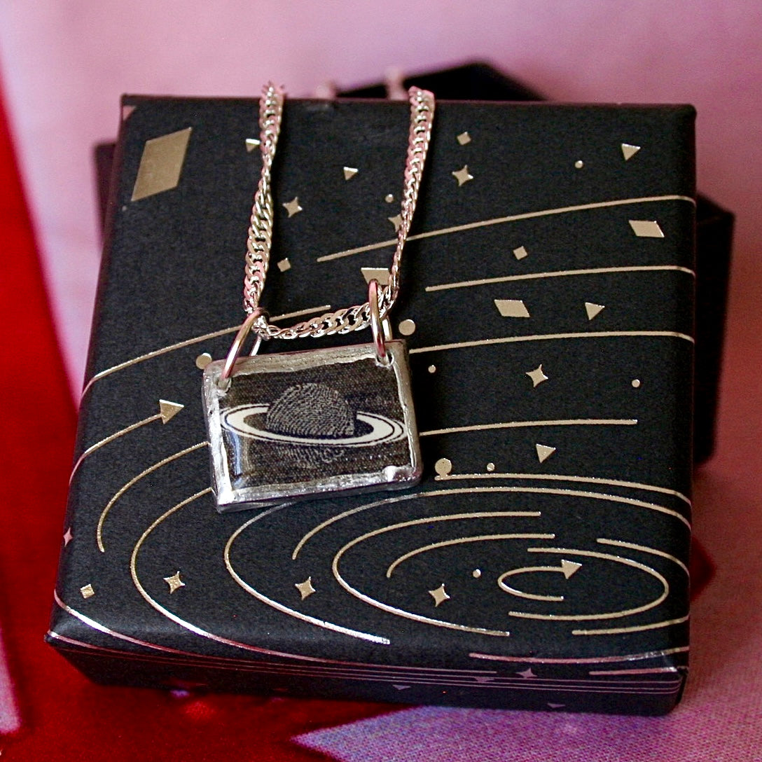 Saturn’s Rings necklace — handmade black & white rectangular polymer clay Saturn charm with metallic silver-black paint on 20" 925 sterling silver chain. Minimal cosmic astrology space jewelry; gift-ready black celestial box. Ready to ship in 1–3 days.