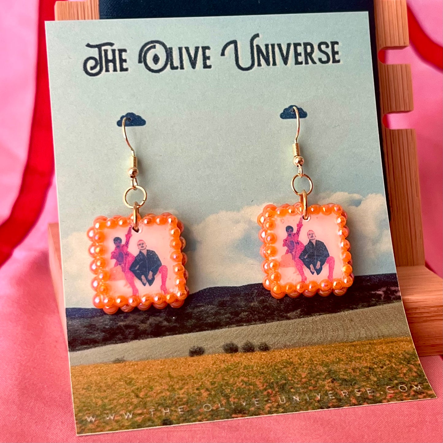 Handmade queer art earrings featuring polymer‑clay square charms with a “Strike a Pose” design, iridescent orange pearl drops, and 18k gold‑plated hypoallergenic findings – lightweight square charms, LGBTQ‑pride, statement piece, ready to ship in 1–3 days.
