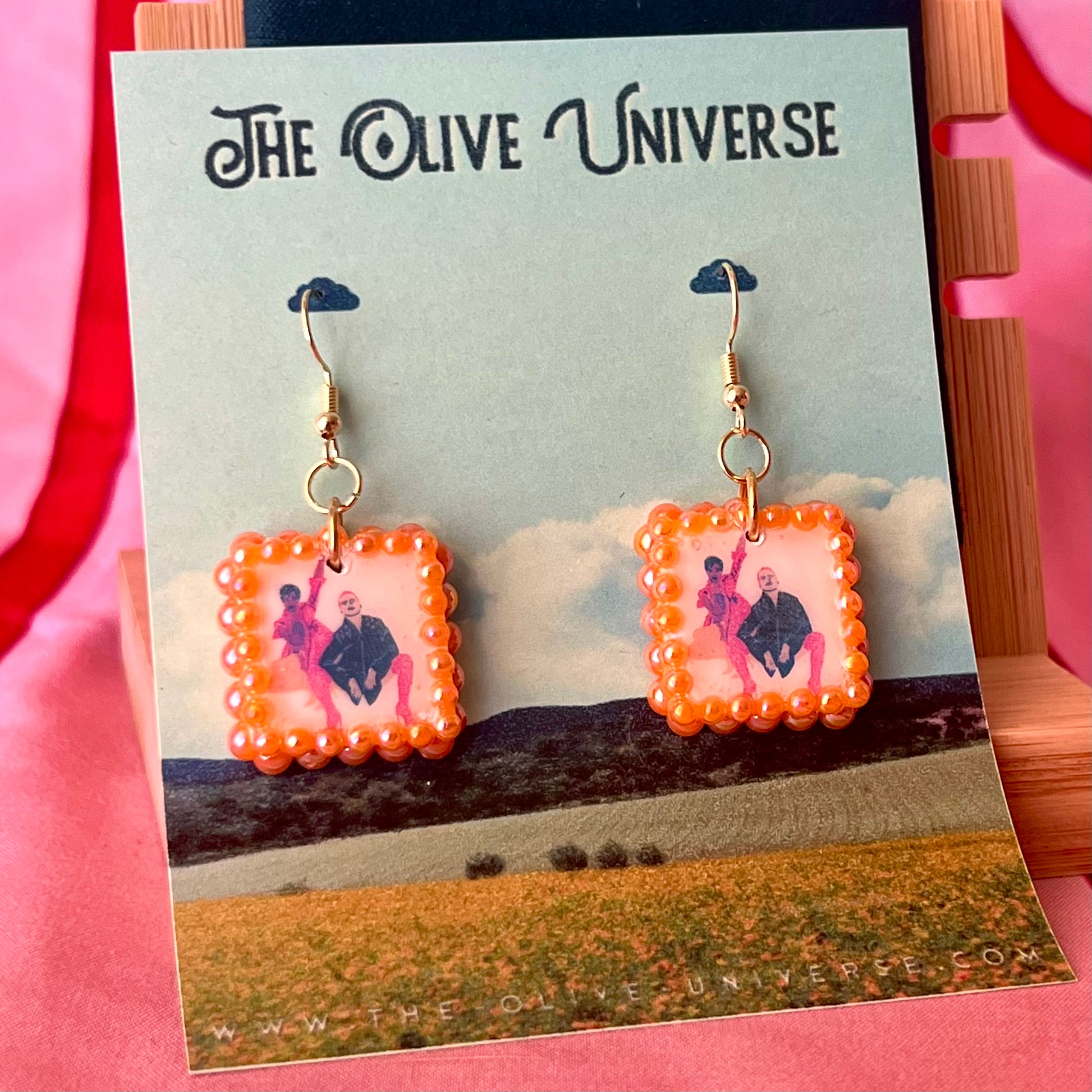 Handmade queer art earrings featuring polymer‑clay square charms with a “Strike a Pose” design, iridescent orange pearl drops, and 18k gold‑plated hypoallergenic findings – lightweight square charms, LGBTQ‑pride, statement piece, ready to ship in 1–3 days.