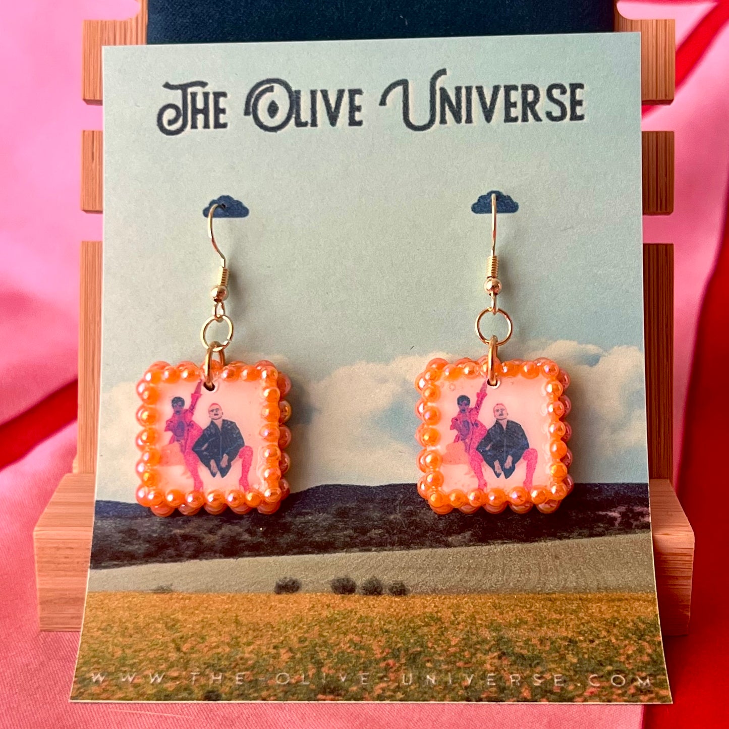 Handmade queer art earrings featuring polymer‑clay square charms with a “Strike a Pose” design, iridescent orange pearl drops, and 18k gold‑plated hypoallergenic findings – lightweight square charms, LGBTQ‑pride, statement piece, ready to ship in 1–3 days.