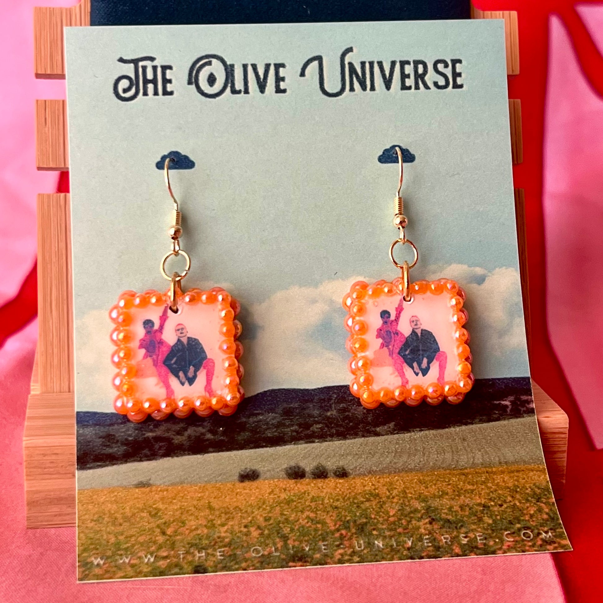 Handmade queer art earrings featuring polymer‑clay square charms with a “Strike a Pose” design, iridescent orange pearl drops, and 18k gold‑plated hypoallergenic findings – lightweight square charms, LGBTQ‑pride, statement piece, ready to ship in 1–3 days.