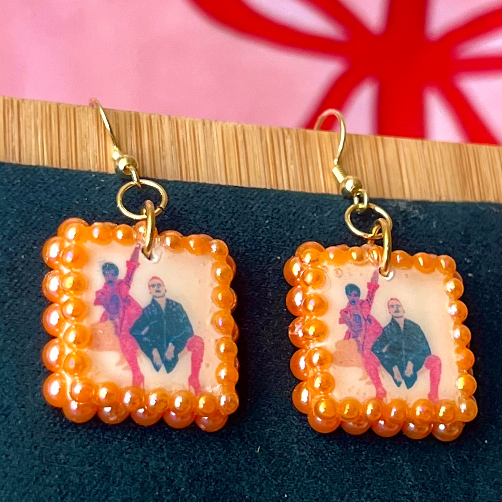 Handmade queer art earrings featuring polymer‑clay square charms with a “Strike a Pose” design, iridescent orange pearl drops, and 18k gold‑plated hypoallergenic findings – lightweight square charms, LGBTQ‑pride, statement piece, ready to ship in 1–3 days.